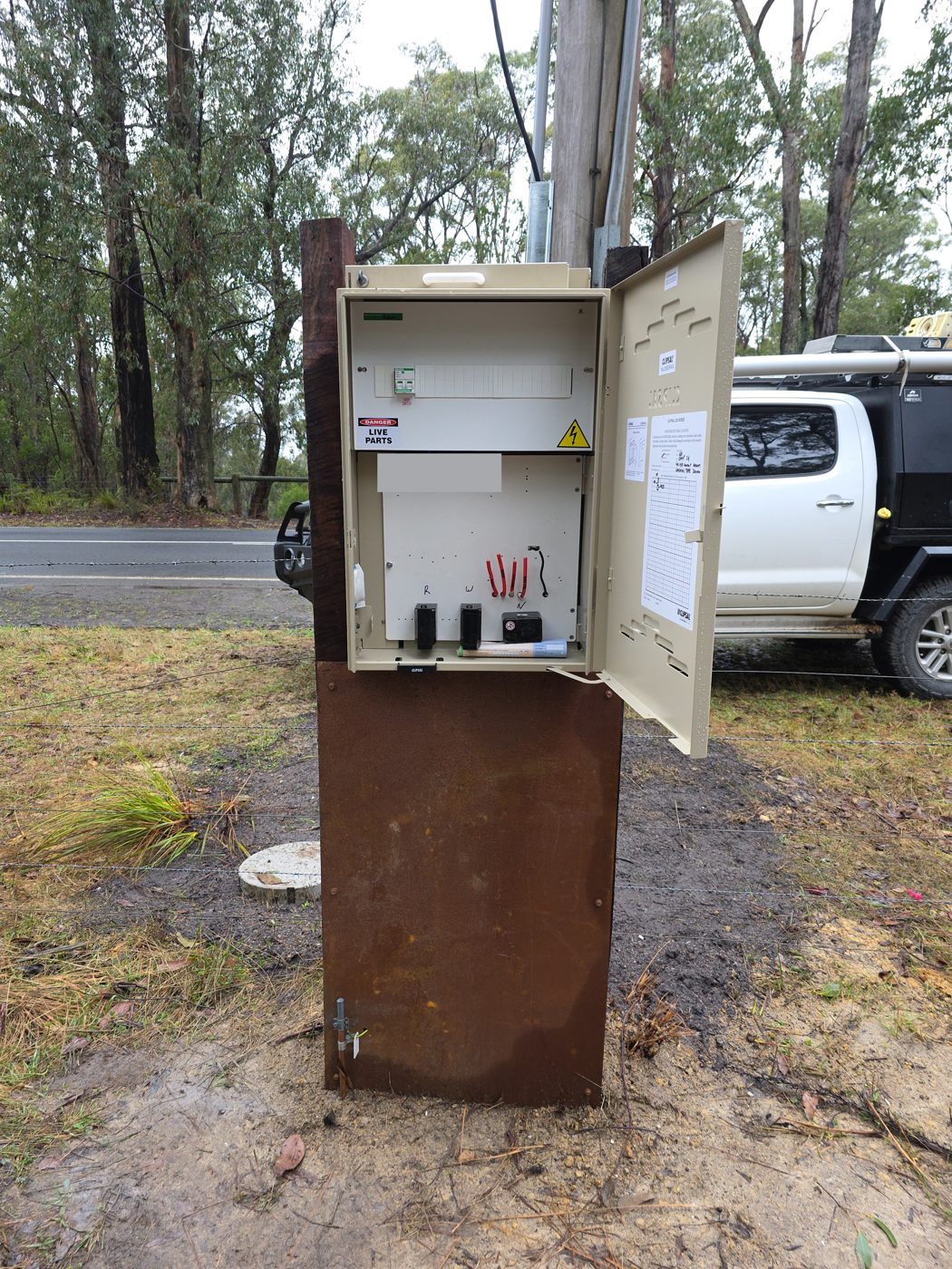 New meter box connection beside a power pole with the door open, showing the main switch, circuit breakers and meter connections