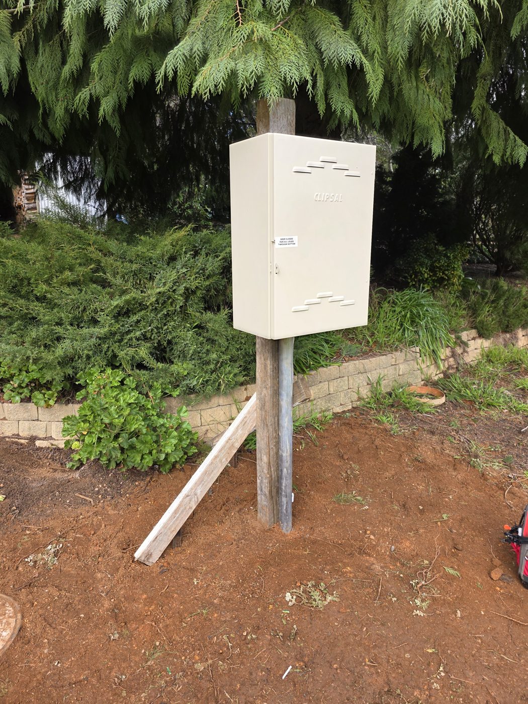 Temporary construction power supply box mounted on a pole and braced with timber
