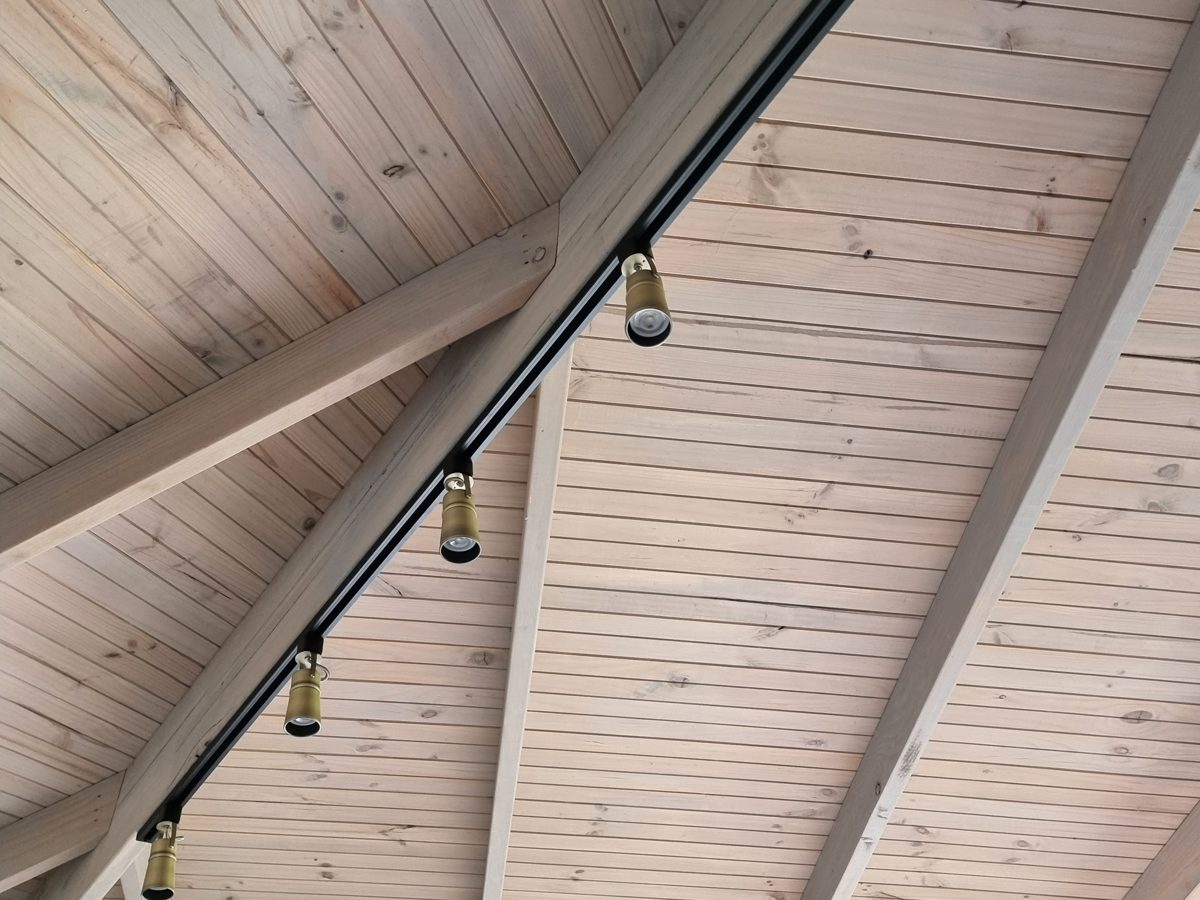 Brass spotlights on a black track along a timber ceiling beam